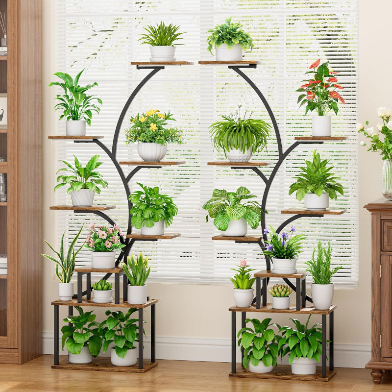 Decorative plant stand with various potted plants against a neutral wall.